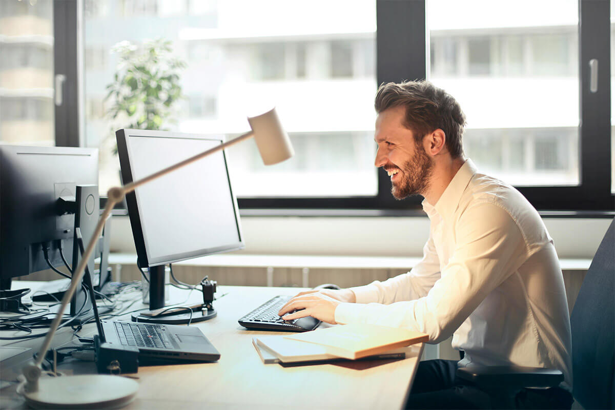 Um homem profissional trabalhando em um computador desktop em um escritório moderno.